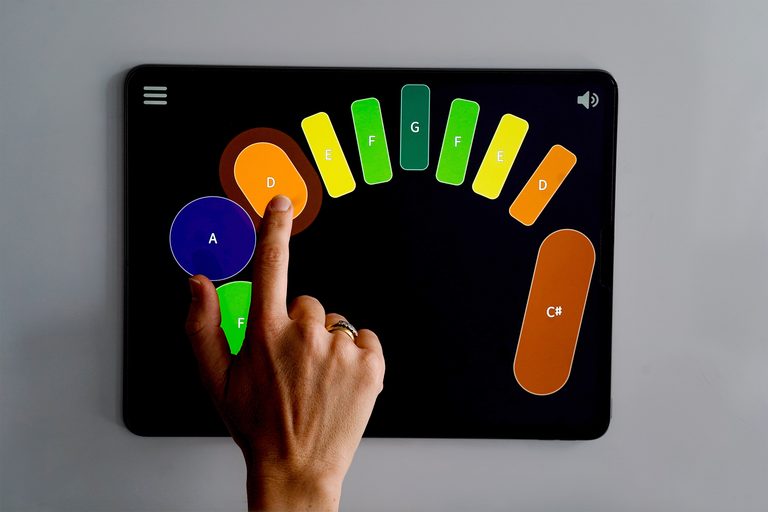 An array of colourful shapes make up a Clarion pattern on an iPad. A hand plays the pattern.